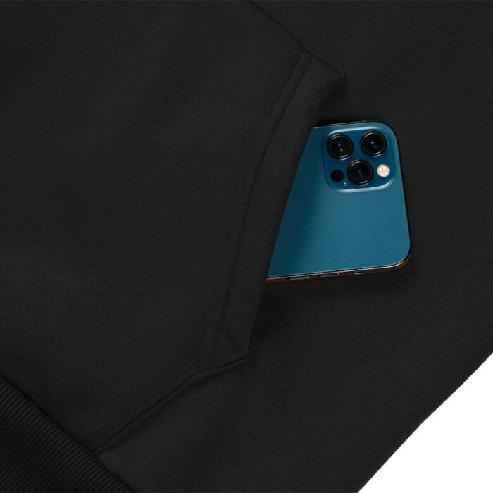 Close-up of the kangaroo pocket on a black hooded sweatshirt with a blue smartphone partially inserted.