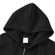 Interior view of the hood of a black zip-up hooded sweatshirt, showing the drawstrings and a white garment tag.