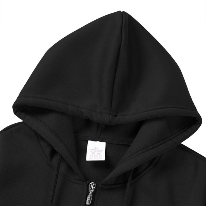 Interior view of the hood of a black zip-up hooded sweatshirt, showing the drawstrings and a white garment tag.