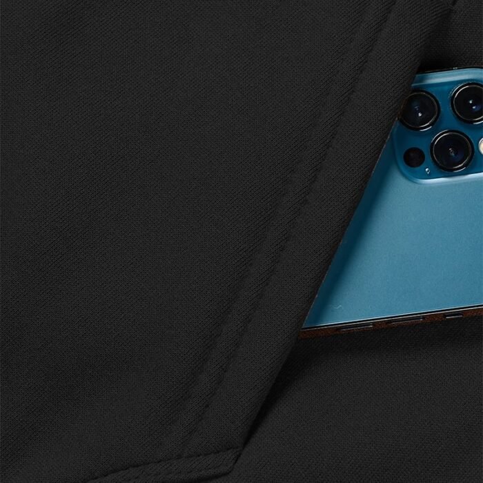 Close-up of the side pocket on a black zip-up hooded sweatshirt with a blue smartphone partially inserted.