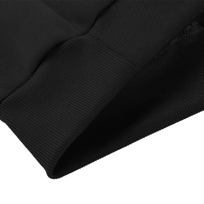 Close-up of the interior of the ribbed hem at the bottom of a black hooded sweatshirt.